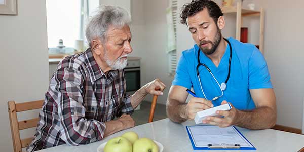 Male nurse with older male patient discussing medication